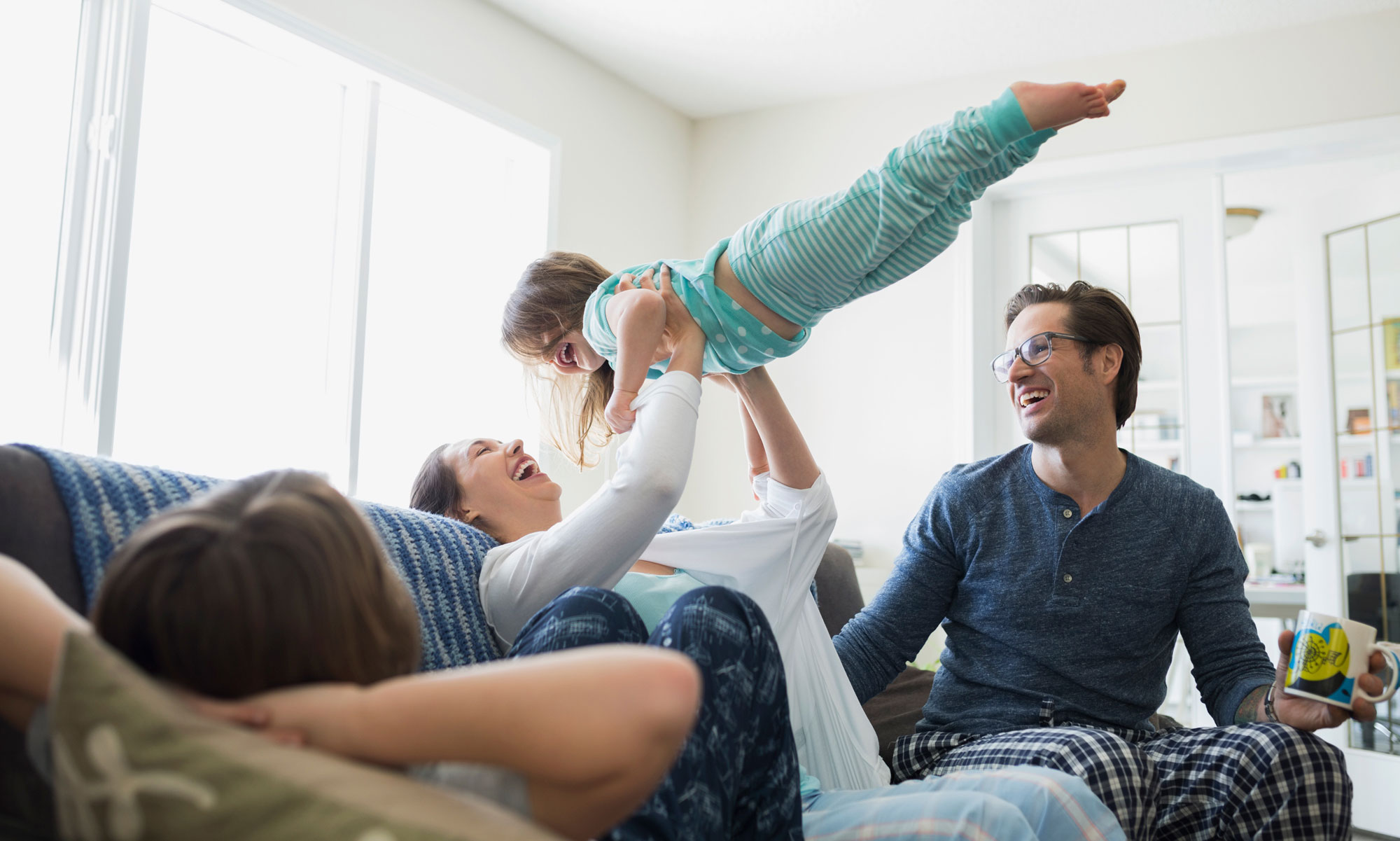 Pyjamasklädd barnfamilj busar i soffan